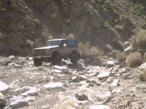 1990 Ford Bronco II - A Ford Bronco II navigates a rocky, off-road terrain in a mountainous area.