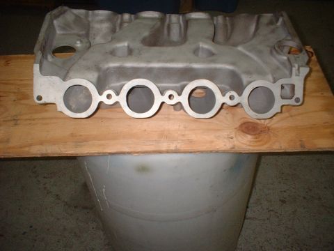 1965 Ford 427 - An aluminum intake manifold is shown, resting on a wooden surface.