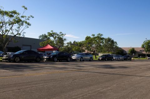 2006 Cadillac STS - Multiple Cadillac sedans are lined up in a parking lot under a clear blue sky.