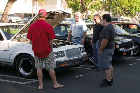 2006 Cadillac STS - A group of men examine a white Buick Regal with its hood open at an outdoor car show.
