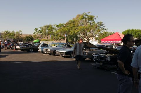 2006 Cadillac STS - A car show displays various vehicles, with people milling around and a red tent in the background.