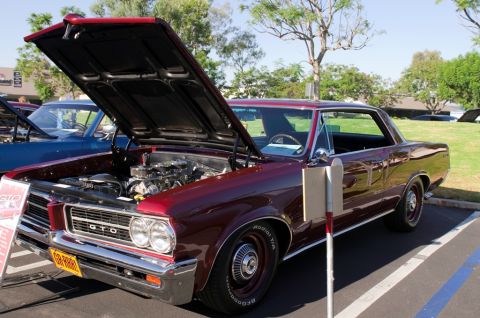 2006 Cadillac STS - A maroon 1964 Pontiac GTO coupe is displayed with its hood open, revealing the engine bay.