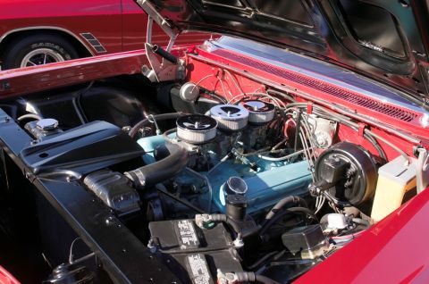 2006 Cadillac STS - The engine bay of a classic car, a V8 engine with triple carburetors and a red vehicle visible behind it.