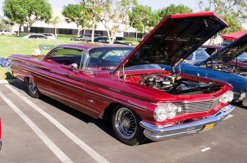 2006 Cadillac STS - A red 1959 Pontiac Bonneville is parked with its hood open, alongside other vehicles.