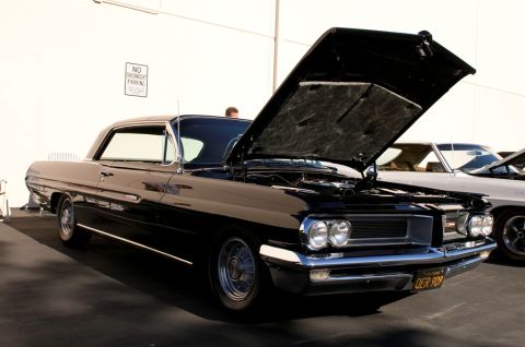 2006 Cadillac STS - Black 1961 Pontiac Catalina two-door hardtop, hood open, parked next to another vehicle.