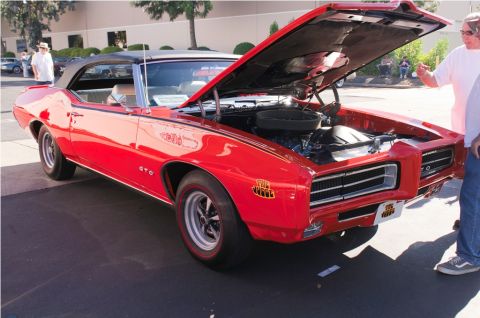 2006 Cadillac STS - A classic red Pontiac GTO convertible is displayed with its hood open, revealing the engine compartment.