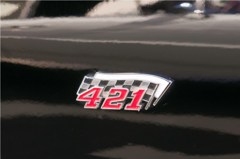 Black car with a chrome and red 421 badge a checkered flag