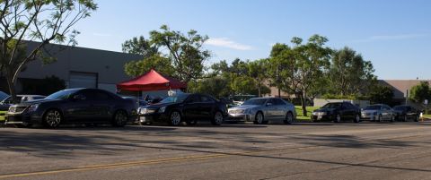2006 Cadillac STS - A line of Cadillacs are parked on the street in front of a building with trees.