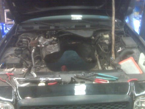 2001 Ford Crown Victoria - Tools and an air filter are laid out in the engine bay of a vehicle. The Supermotors.net logo is visible at the bottom right.