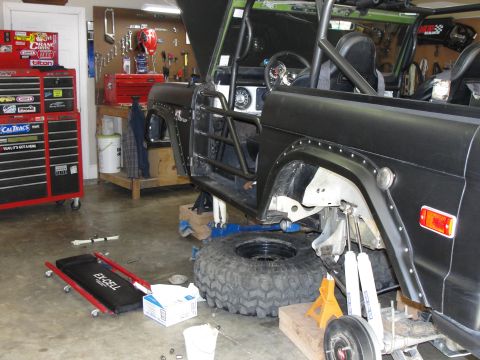 1967 Ford Mustang - A 1966 Ford Bronco is shown in a workshop, lifted on jack stands with its doors removed.