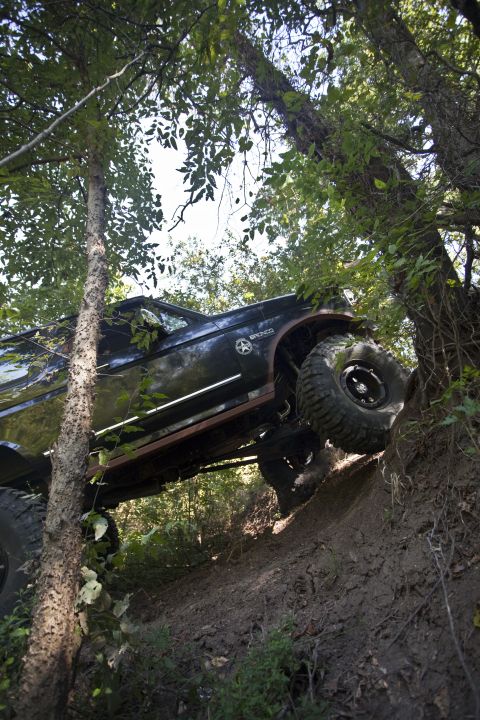 1995 Ford Bronco - This 1995 Ford Bronco navigates a challenging off-road course, its tires digging into the mud as it ascends a steep hill.