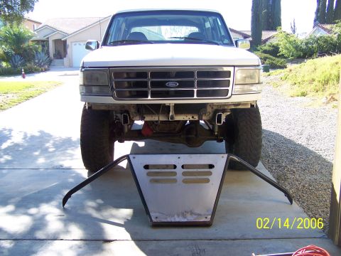 1995 Ford Bronco - Front view of a white 1995 Ford Bronco, with an aftermarket skid plate positioned in front of it.