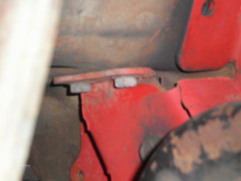 1995 Ford Bronco - Close-up of a red metal bracket with visible bolts and signs of wear and tear.