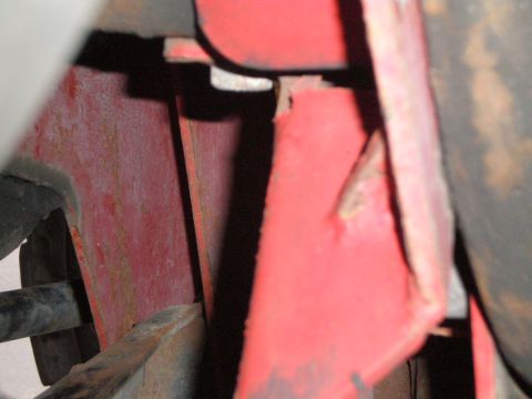 1995 Ford Bronco - Detail of red painted metal structure with visible rust and a black pipe, likely part of a vehicle's undercarriage.