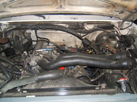 1988 Ford Bronco - Engine bay of a 1988 Ford Bronco, showing intake hoses and fan shroud with caution text.
