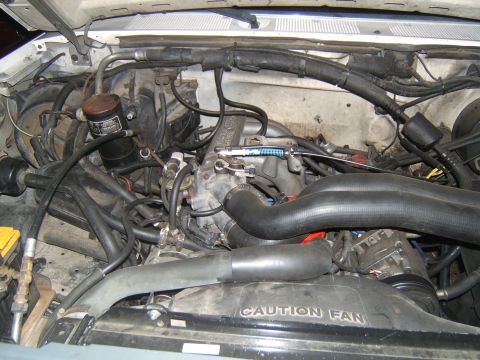 1988 Ford Bronco - The engine bay of a vehicle, showing various mechanical parts and wiring.