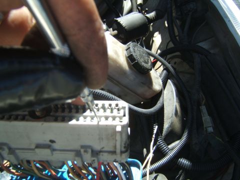 1988 Ford Bronco - A person is working on the wiring harness and electrical connectors under the hood of a vehicle.