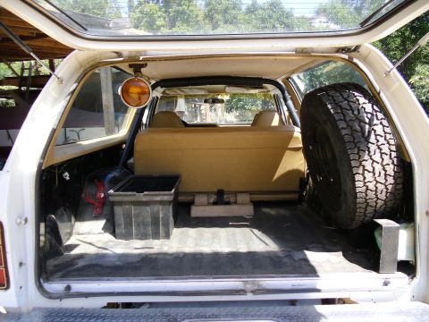 1987 Dodge 1500 - View into the cargo area of an SUV, a spare tire mounted on the side and a folded-down rear seat.