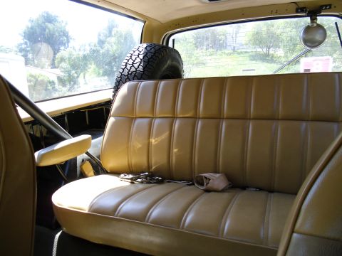1987 Dodge 1500 - Interior view of a vehicle, showing a tan bench seat and a spare tire mounted behind it.