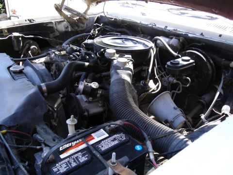 1987 Dodge 1500 - Close-up view of a vehicle's engine bay, showing various components and the battery.