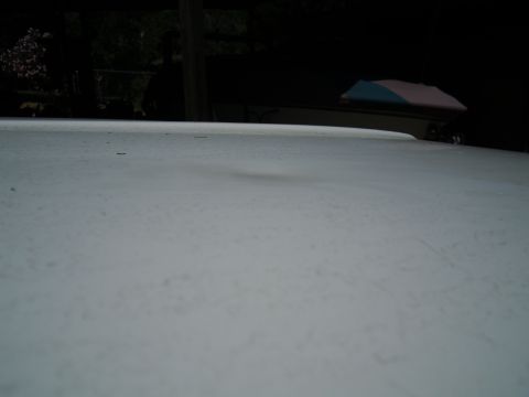 1987 Dodge 1500 - The top of a white truck bed is shown with a dent. The background is dark and out of focus.