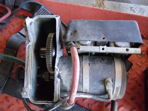 1987 Dodge 1500 - Close-up of a winch motor and its internal gears, with a damaged metal housing.