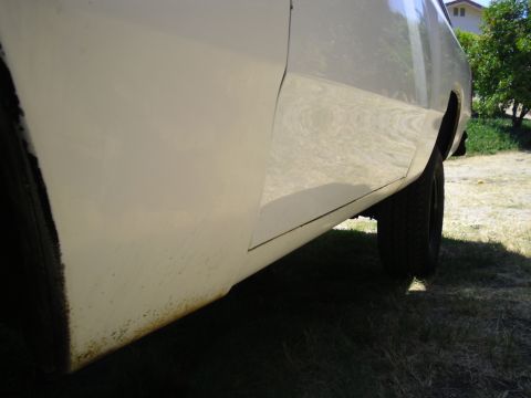 1987 Dodge 1500 - Close-up of the side panel of a white pickup truck, showing a seam and some rust near the bottom.