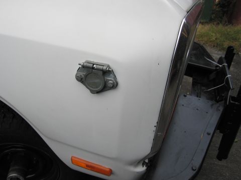 1987 Dodge 1500 - Trailer hitch connector on the fender of a white vehicle.