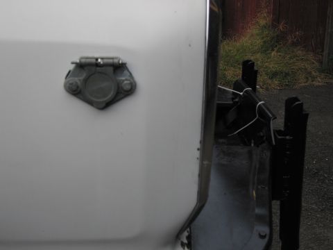 1987 Dodge 1500 - Close-up of a trailer hitch connector mounted on the side of a white vehicle.