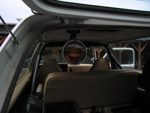 1987 Dodge 1500 - Interior view of a vehicle with a spotlight mounted overhead, showing tan seats and a roll bar.