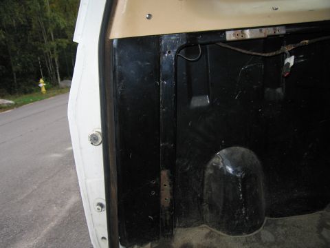 1987 Dodge 1500 - Close-up of the interior of a truck bed, revealing the wheel well and black protective lining.