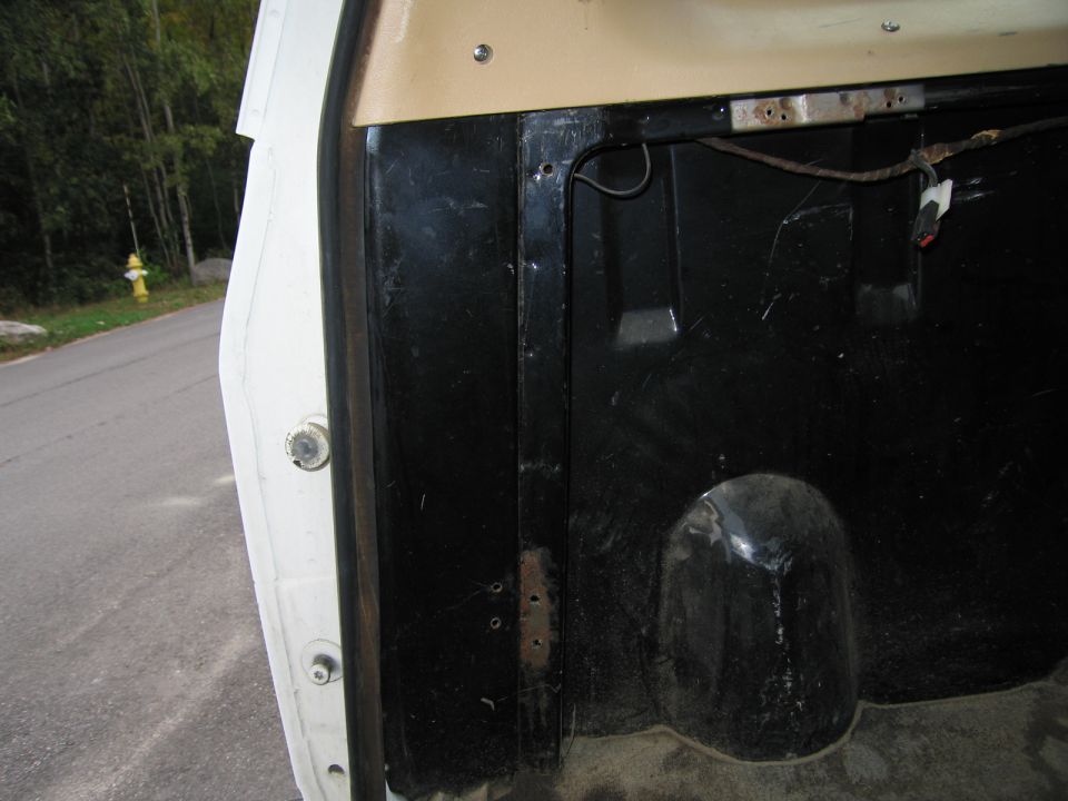 Interior view of a truck bed showing black lining and a wheel well