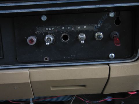 1987 Dodge 1500 - A close-up view of an aftermarket dashboard switch panel with various toggle and rocker switches.