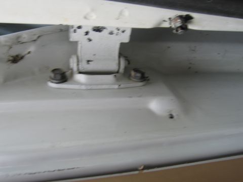 1987 Dodge 1500 - Close-up view of a white door hinge, showing bolts and signs of wear and tear.