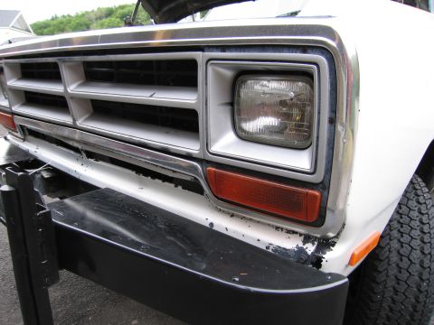 1987 Dodge 1500 - Close-up of the front grille and headlight assembly on a white 1987 Dodge 1500 pickup truck.