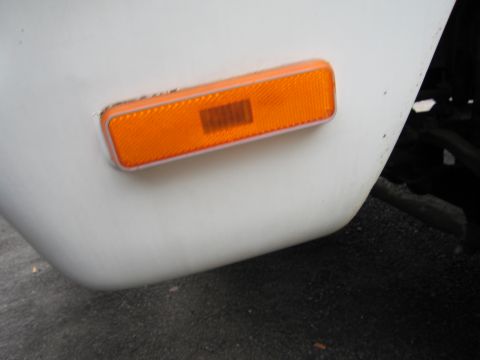 1987 Dodge 1500 - Orange side marker light assembly on the front fender of a white vehicle.