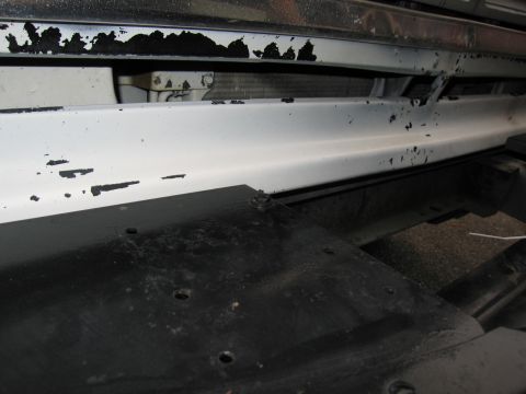 1987 Dodge 1500 - Close-up view of a white front bumper showing signs of wear and tear, with a black undercarriage visible.