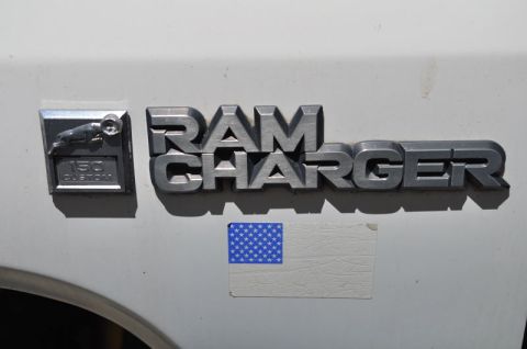 1987 Dodge 1500 - Close-up of a Ram Charger 150 Custom emblem on a white vehicle, with an American flag sticker.