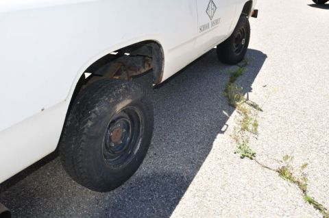 1987 Dodge 1500 - A white pickup truck, possibly from a school district, is parked on the side of a road.