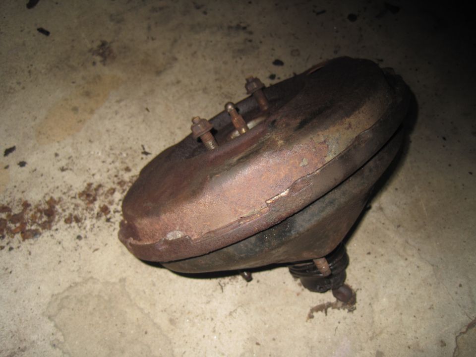 Rusty brake booster with bolts on a concrete floor