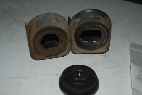 1982 Ford Bronco - Two metal brackets with hexagonal and rectangular openings, alongside a rubber mount with a threaded insert.