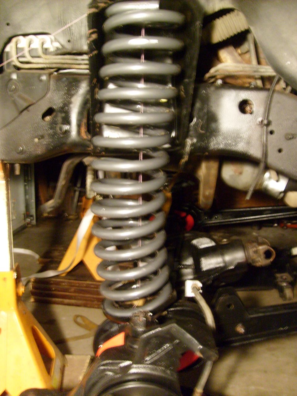 Gray coil spring and black suspension parts on yellow jack stands