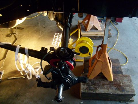 1986 Ford Bronco - Vehicle suspension component being worked on, supported by jack stands in a garage setting.