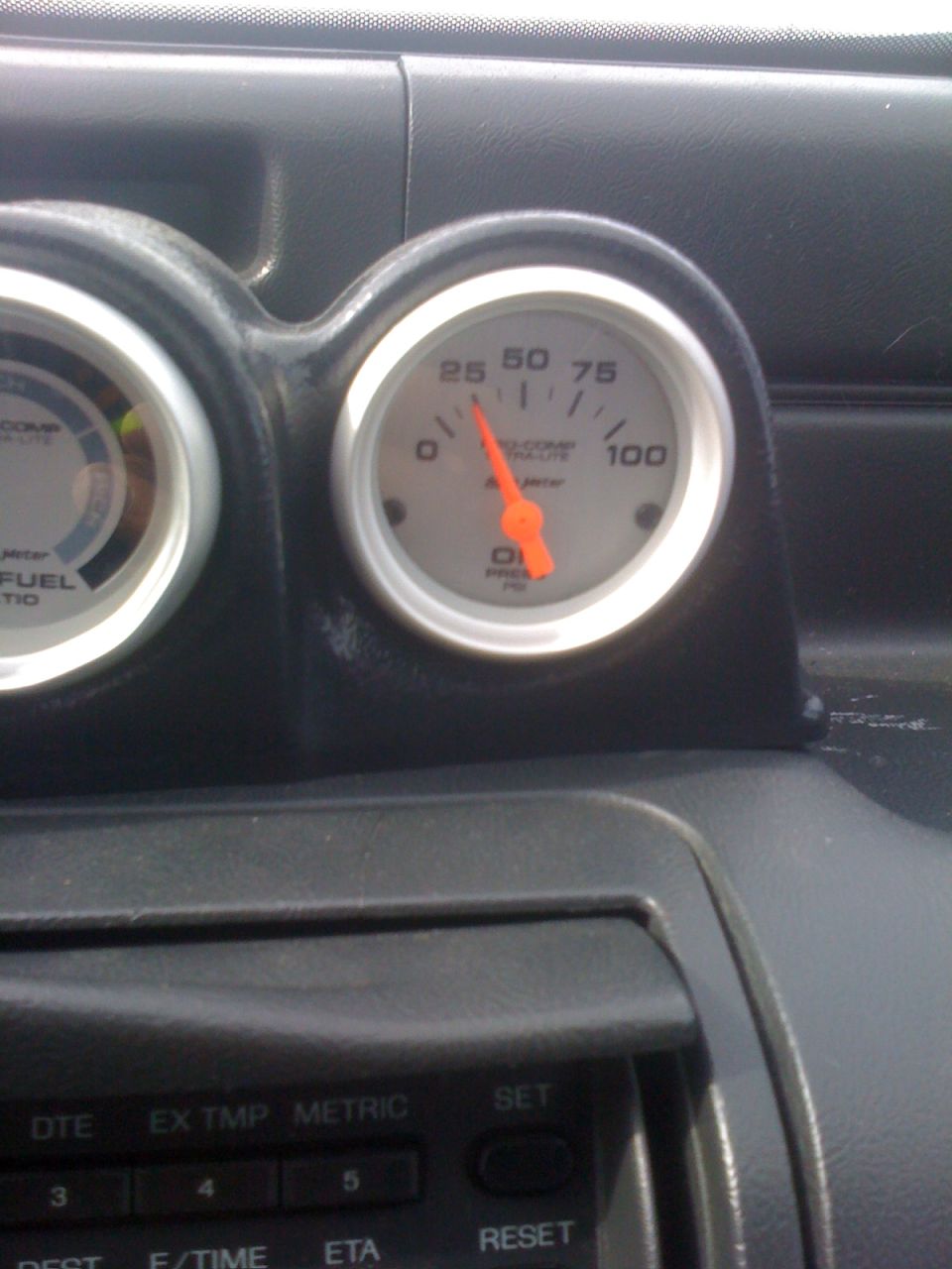 Close-up of dashboard with oil pressure and fuel gauges. The oil pressure gauge reads around 20 PSI