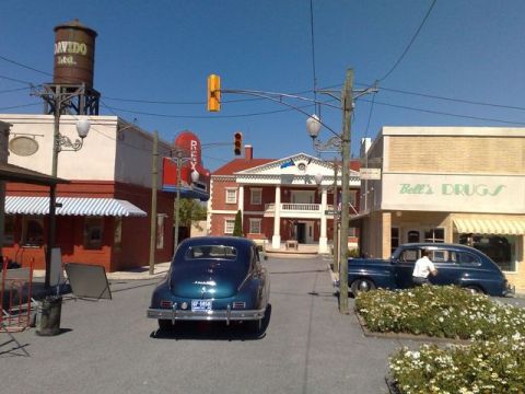 1991 Ford LTD Crown Victoria - A street scene with two vintage sedans and period architecture under a clear blue sky.