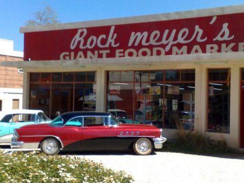 1991 Ford LTD Crown Victoria - A classic red and black coupe is parked in front of a vintage grocery store.