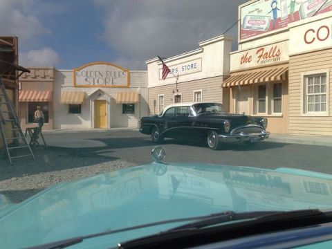 1991 Ford LTD Crown Victoria - A classic two-tone sedan is parked on a street with storefronts in the background.