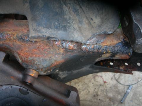 1984 Ford Bronco - This image shows a heavily rusted and welded section of a vehicle's frame, likely from a repair or modification.