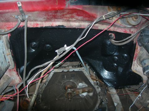 1984 Ford Bronco - Firewall area of an engine bay, coated in black, with visible wiring and transmission components.