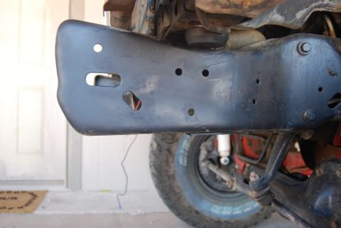 1982 Ford Bronco - Close-up view of the undercarriage and suspension of a vehicle, showing the frame and a tire.